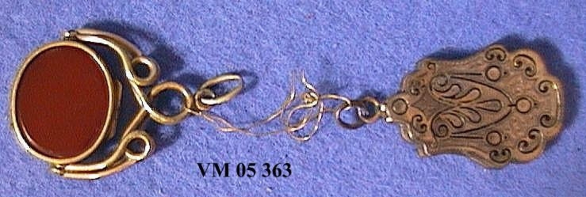 1. Avlång berlock (medaljong) med frimurarsymbol på baksidan. L. 2,9 cm. B. 2 cm.

2. Oval medaljong, troligtvis silver.Röd sten.  L. 2,7 cm  B. 2,4 cm