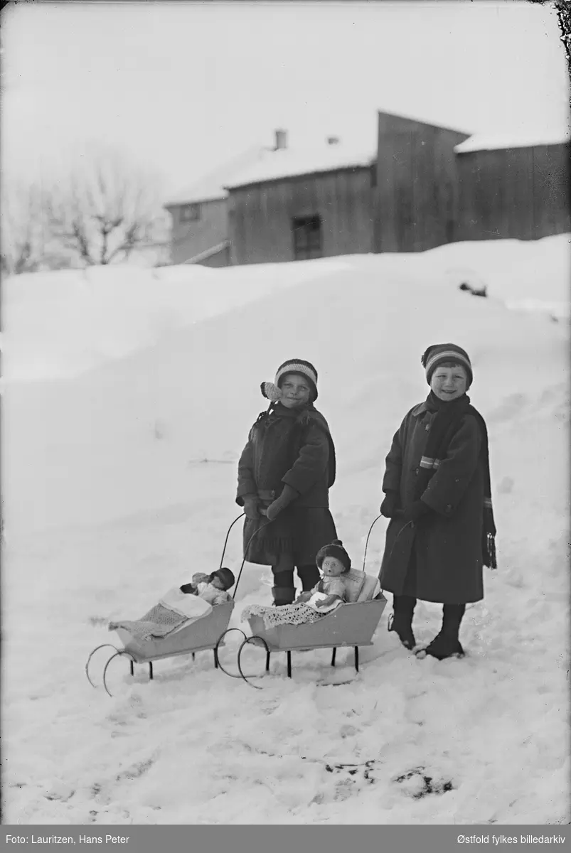 Piker med dukkeslede, altså dukkevogn med meier i Moss. Fotografens datter med venninne i sneen, ca 1922-23. Fra venstre: Vera Mostrøm og Dagar Lauritzen, fotografens datter.