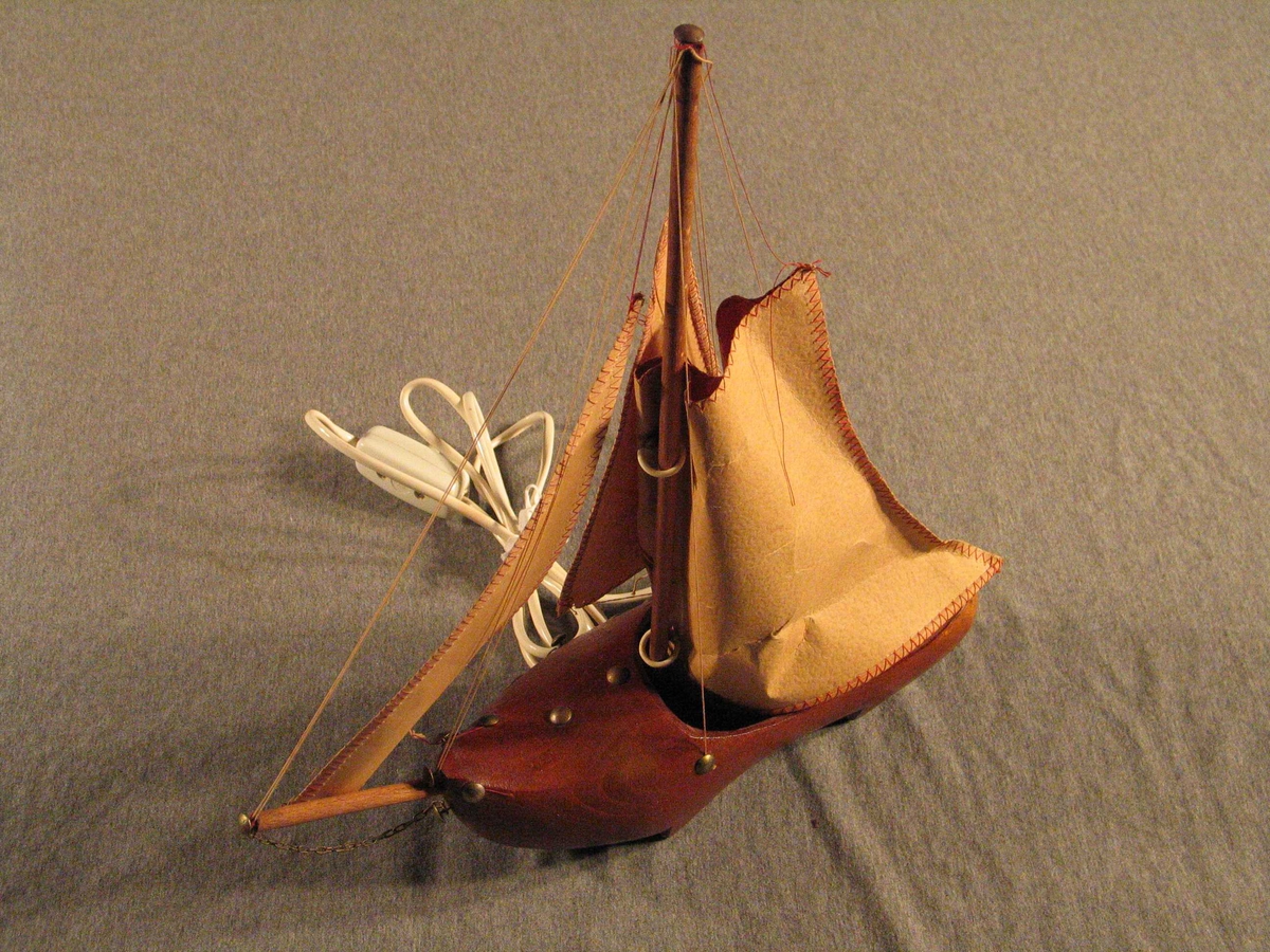 Treskobåt med full seglføring og lampe inni seglet. Teikning av seglbåtar på segla.