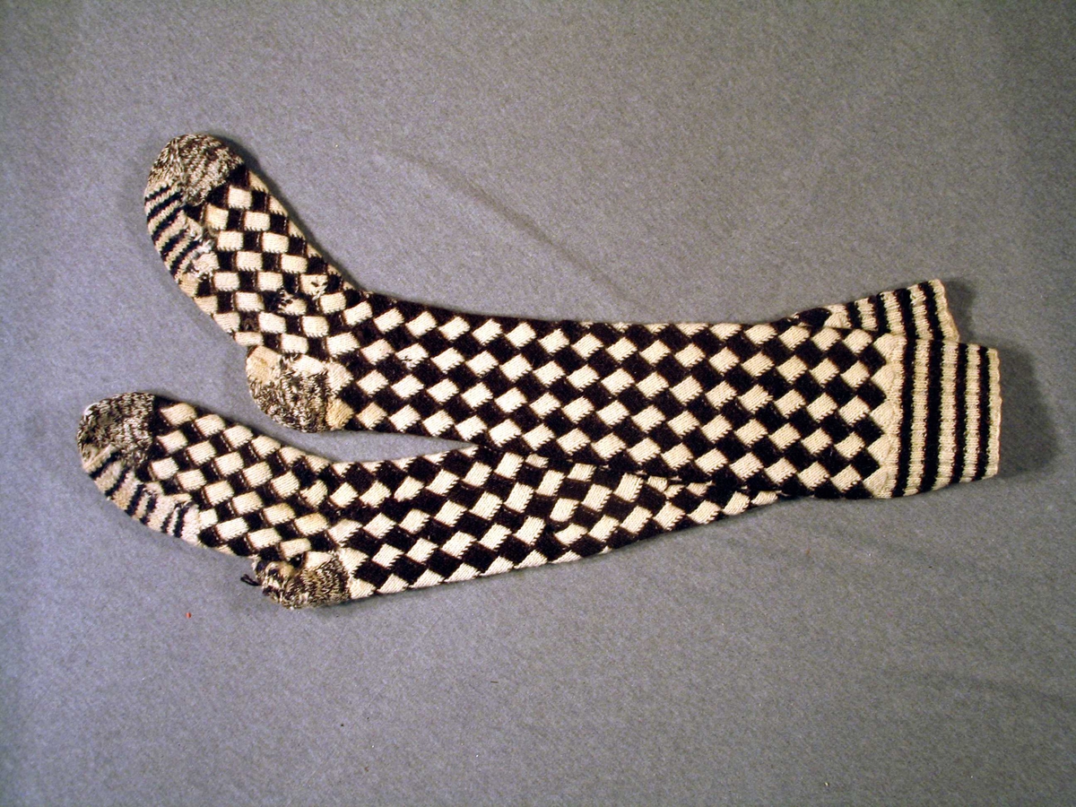 Eitt par kontestrikka sokkar (neverkont-teknikk), vrangbord med striper i 2 rette og to vrange, 5 omg. i kvar stripe. Kontstrikkinga (dial: spons som tyder rute) er gjort med 4 masker i breidda, 11 omg. i kvar rute.Foten på begge sokkane er stoppa med melert garn på hælen, same tråden er brukt for å strikke opp att tåspissane. Under begge fotballane er ei bot som er strikka i striper av blått og kvitt garn, truleg klipte av eit anna plagg. den eine sokken er stoppa også på leggen.
Sjå også SuM. lnr. 1988-13.