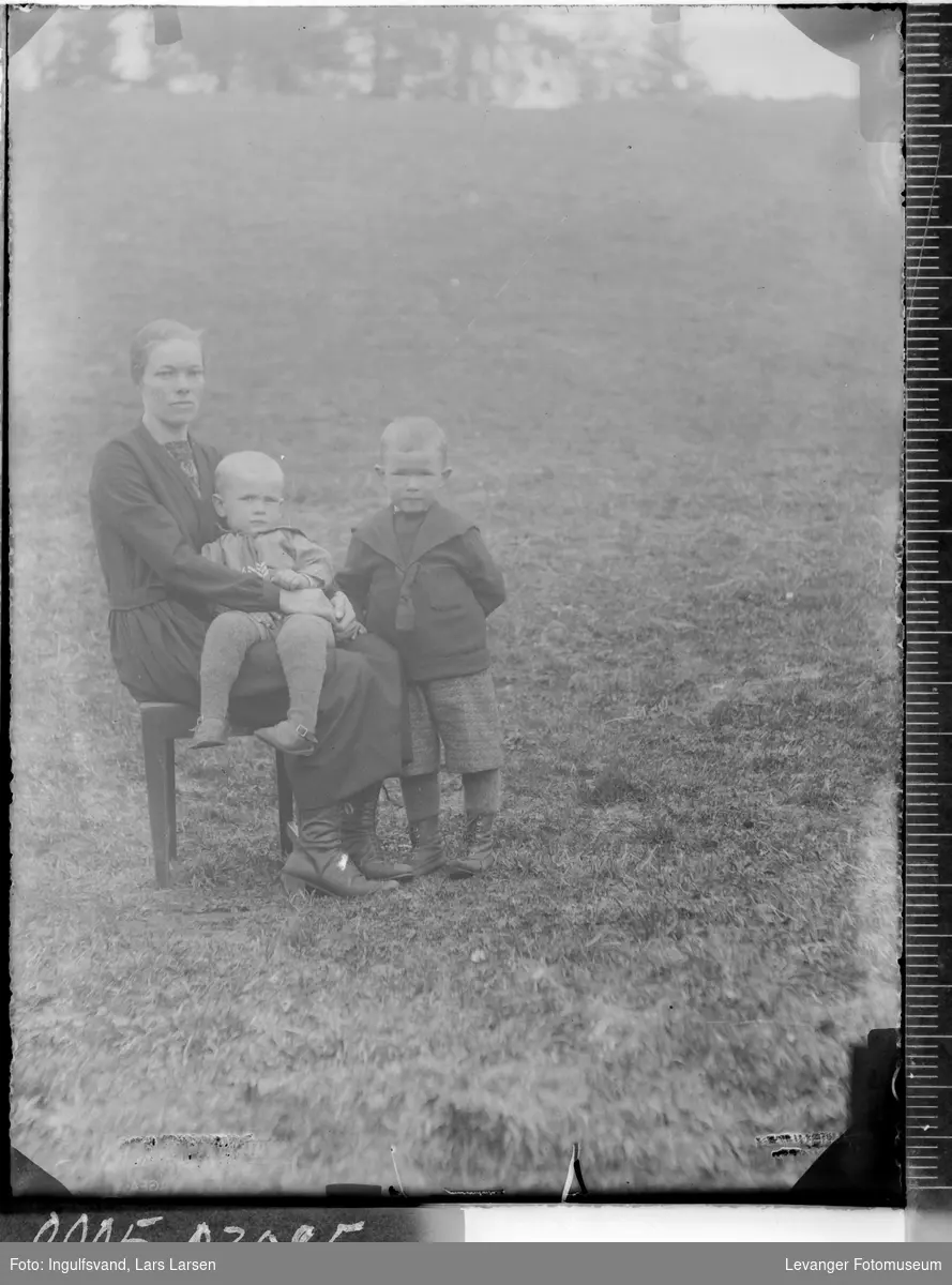Gruppebilde av en sittende kvinne med to barn.