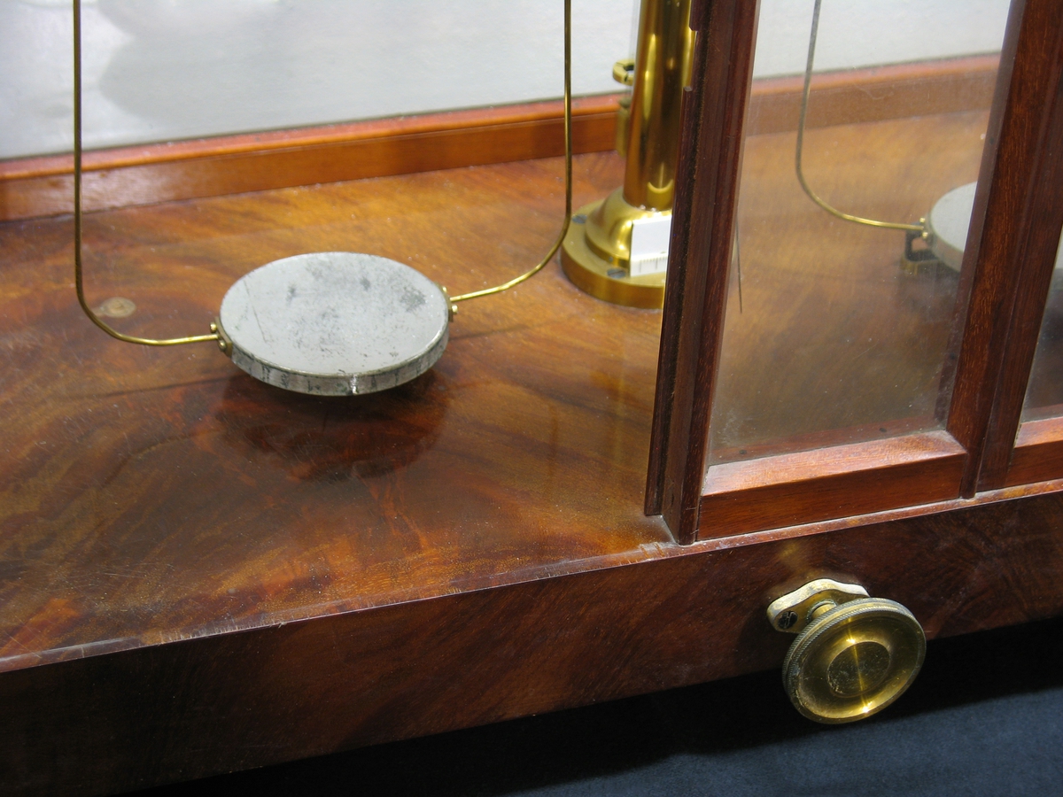 En precisionsvåg i ett skåp med glasväggar och dörrar.