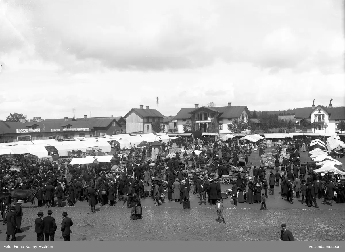 Marknad på stortorget i Vetlanda. I bakgrunden syns järnvägshotellet (senare stadshotellet) och Emma Lundgrens fotoateljé.