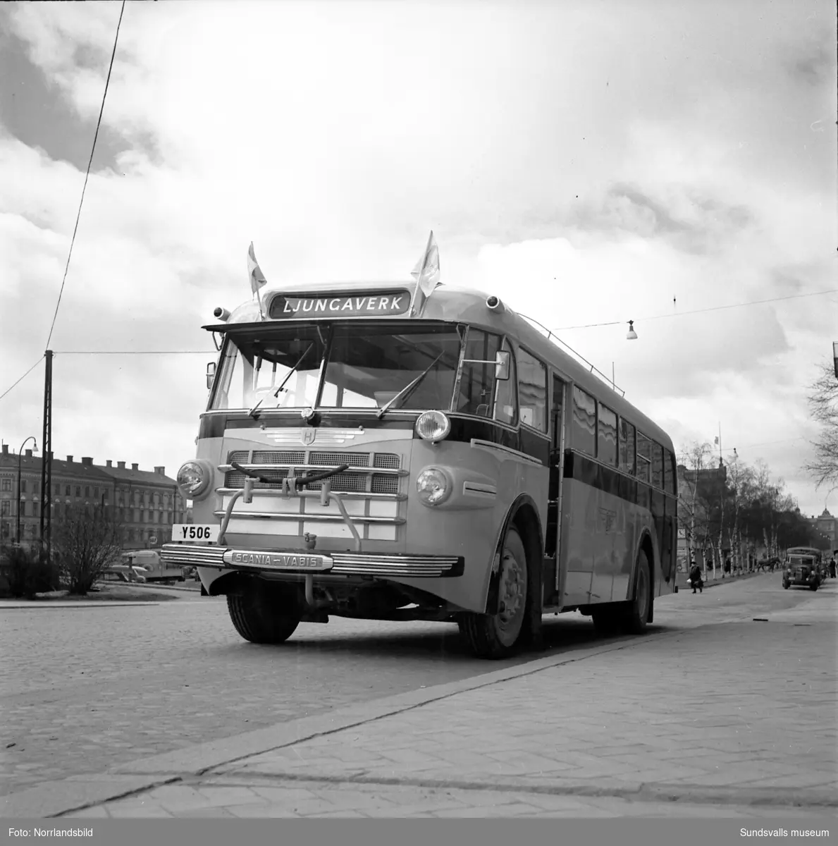 Nya Ljungaverksbussen fotograferad vid Efs-kyrkan på Köpmangatan 2. På den första bilden syns Läroverket längst bort till höger om bussen. En bit bort syns även en hästskjuts som korsar gatan.