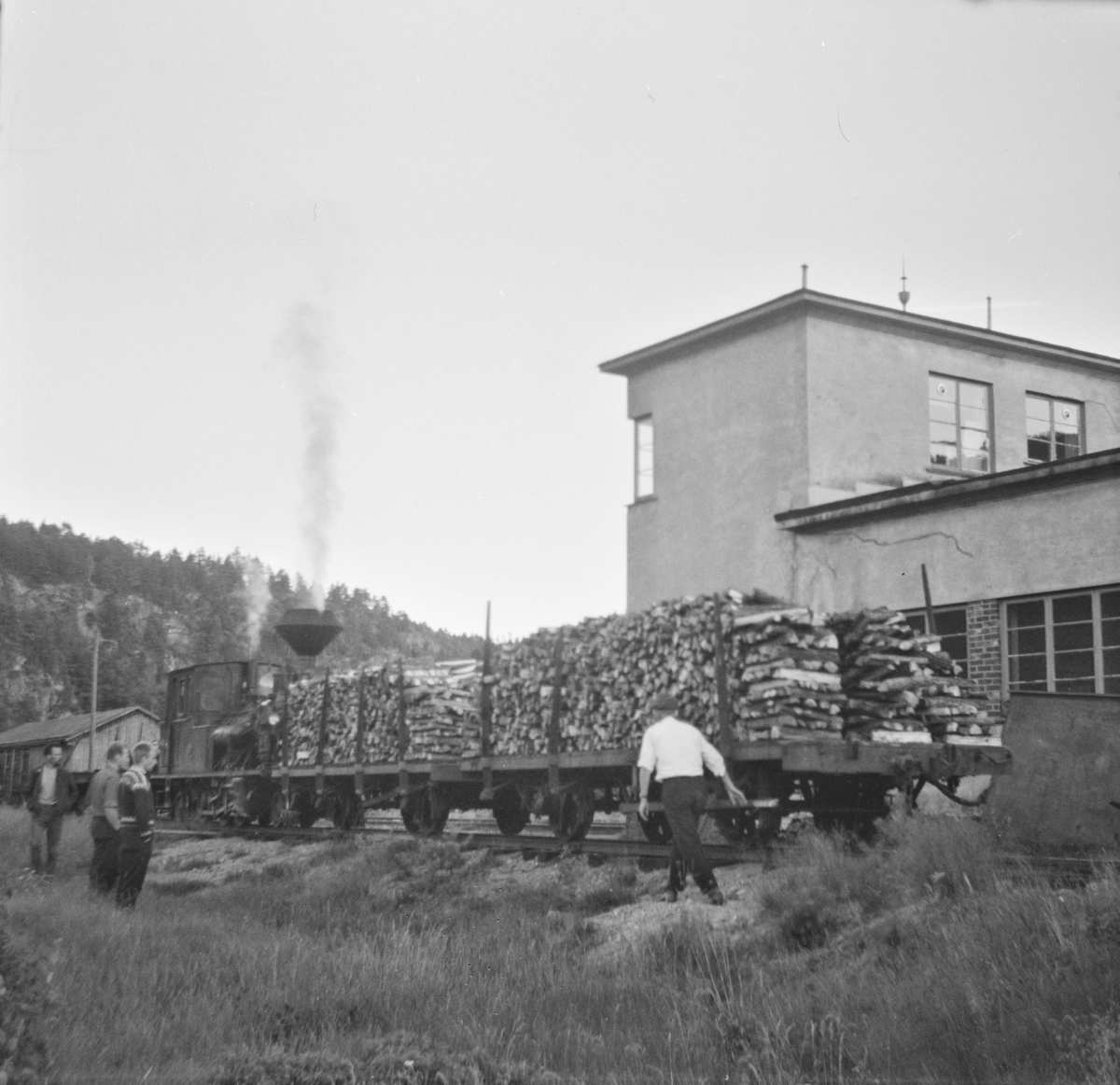 Godsvogner lastet med ved utenfor Setesdalsbanens verksted på Grovane. I bakgrunnen damplokomotiv type XXI nr. 2.