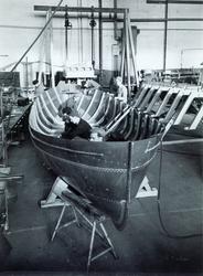 7 menn arbeider med byggingen av en båt.