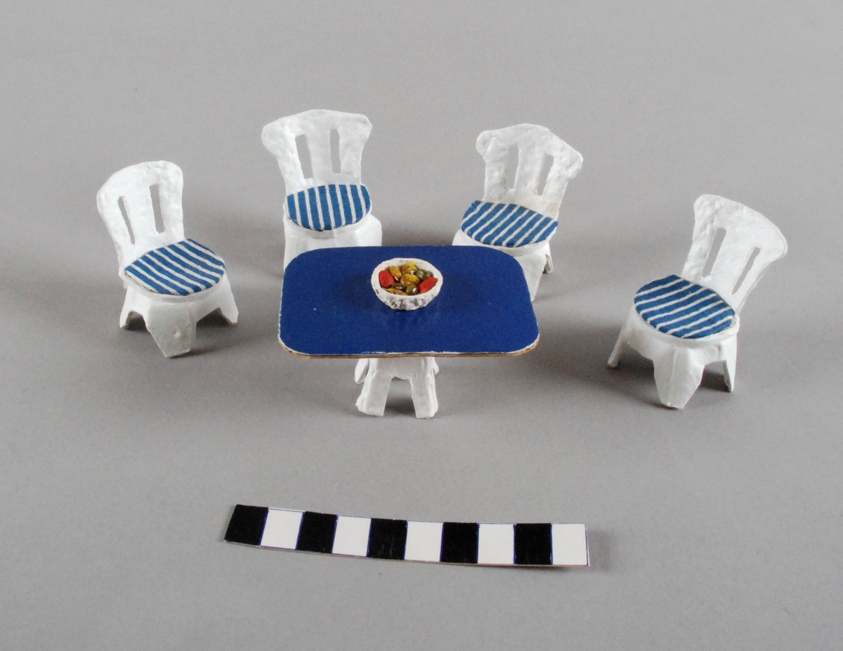 Stuemøblement til dokkehus, med firkantet bord med fruktskål og fire spisestuestolar. med tekstilsete i blå og kvite striper.