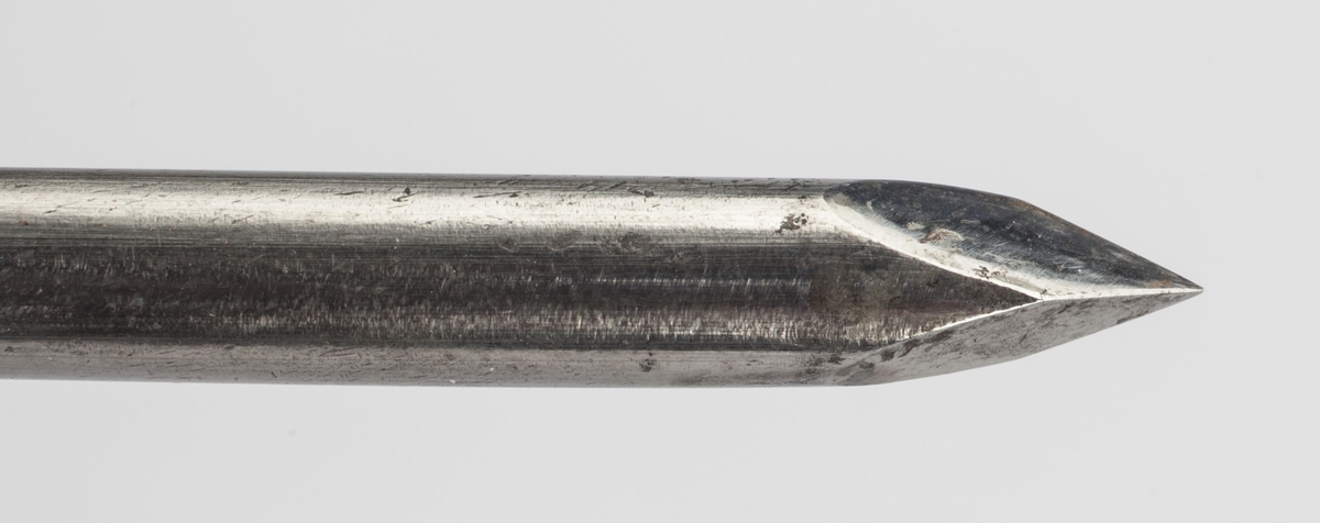 Syllignende redskap i stål med skaft av tre. I tillegg en stålsylinder med en skeilignende ende for å tømme puss fra sår og byller.