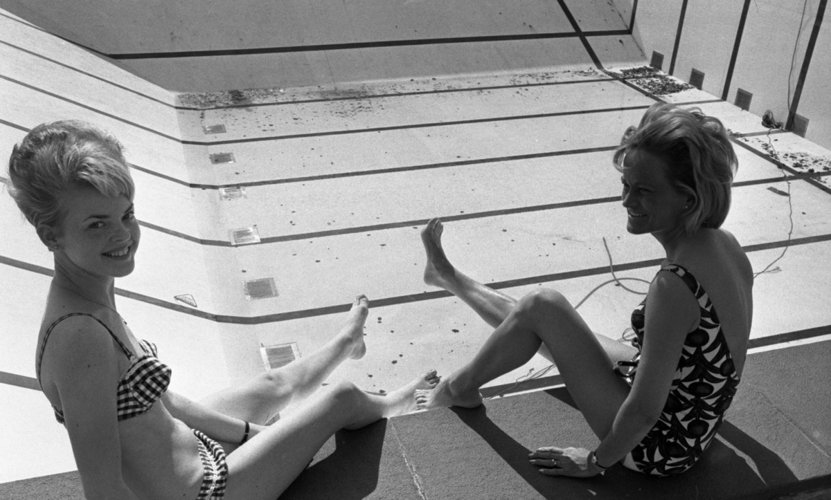 Hej Sommar, Bilskola 3 maj 1966

Två kvinnor - en i bikini och en i baddräkt sitter på kanten till en bassäng på Gustavsviksbadet. Bassängen är för tillfället tömd på vatten. En vattenpump syns vi ena bassängväggen i bakgrunden.











































































































































































































































































or. Han går nedför en kort trappa utomhus.
