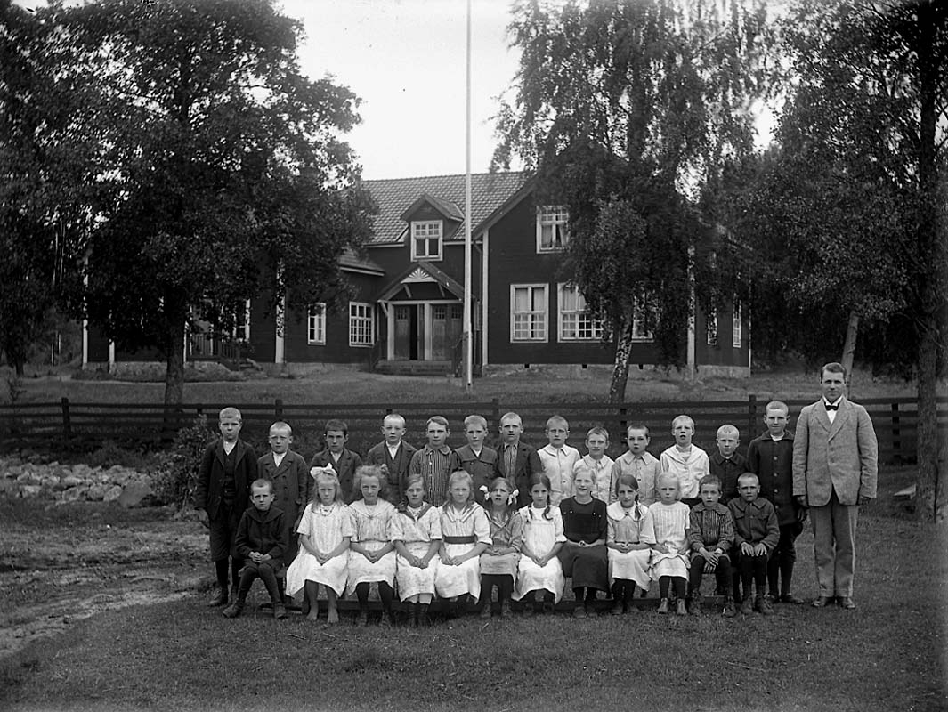 Sandvikens-skola, Skogaholm. Skolbarn med lärare, skolbyggnad i bakgrunden.