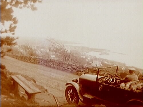 Utsikt över Mölle. Bil i förgrunden. 
Bilen är en Oldsmobile modell 30 från 1923-24 med en 42 hästkrafters sexcylindrig motor. Den registrerades den 2:e april 1924 på fröken Jenny Larsson, Örebro, och fick registreringsnummer T99. År 1930 ägdes den fortfarande av Jenny Larsson.