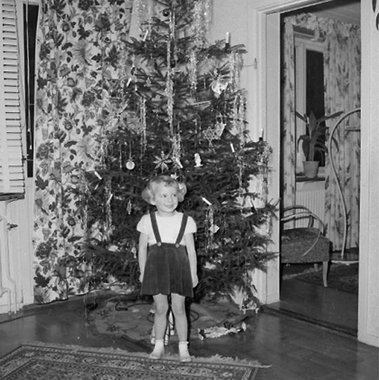 Rumsinteriör, en liten flicka vid julgranen.
Rulle Molin (beställare).