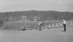Tre personer i aktivitet på gårdsplassen på Linderud Gård. I