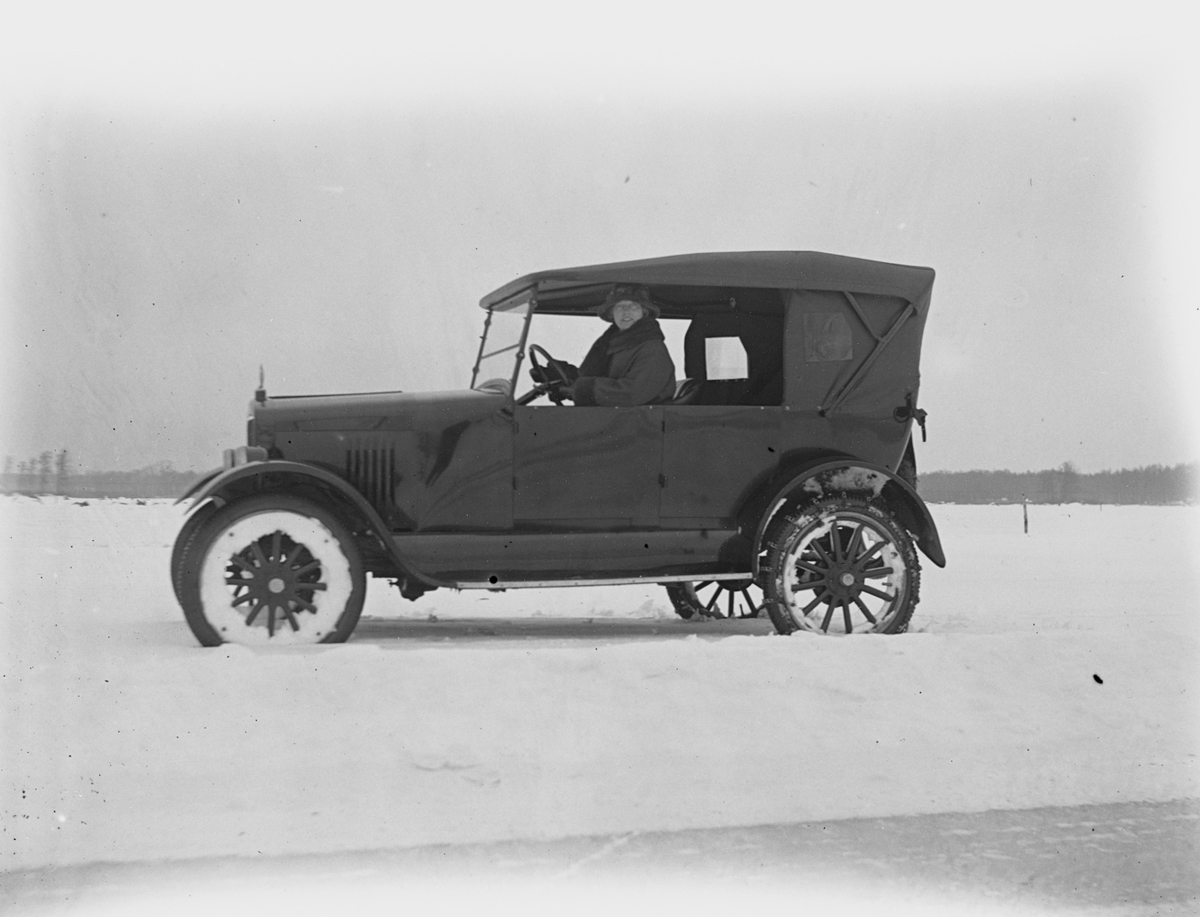 En kvinna i en bil.
Hjälmaren den 17 februari. 
Bilen på denna bild är en Gray Touring från 1922. Den ser ut att vara ny vid fototillfället eftersom den har en temporär registreringsskylt (interimsskylt).