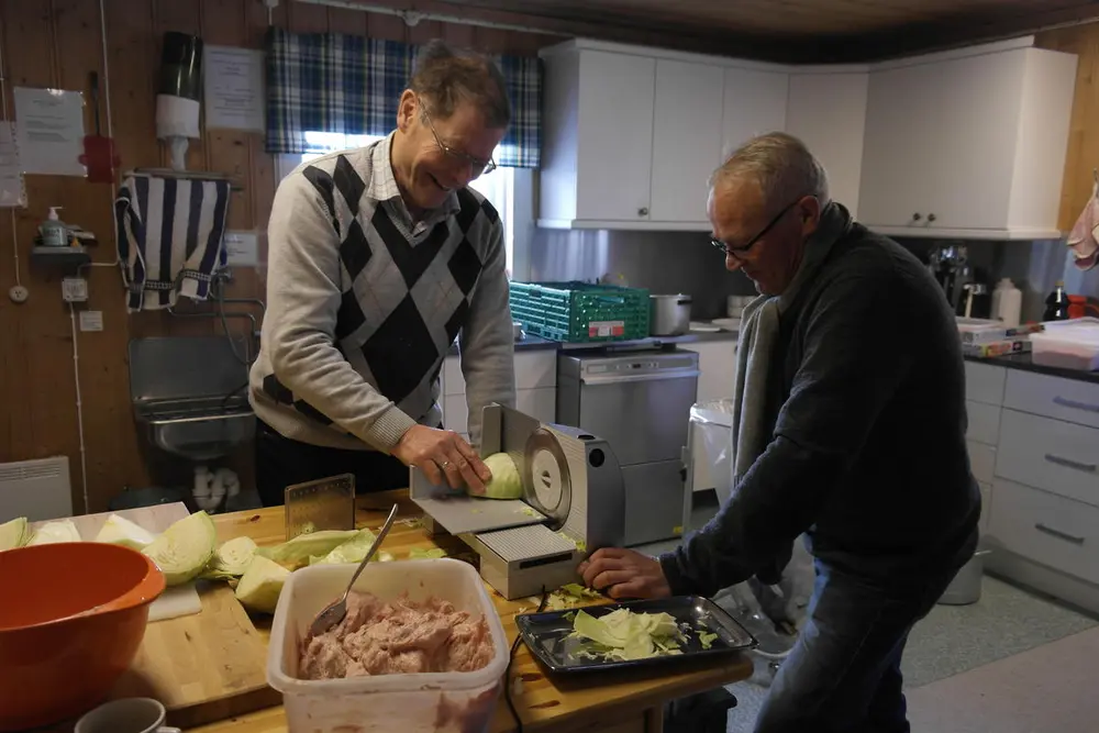 to menn skjærer kål til surkålen som skal serveres på  "Førjul på bygdetunet".