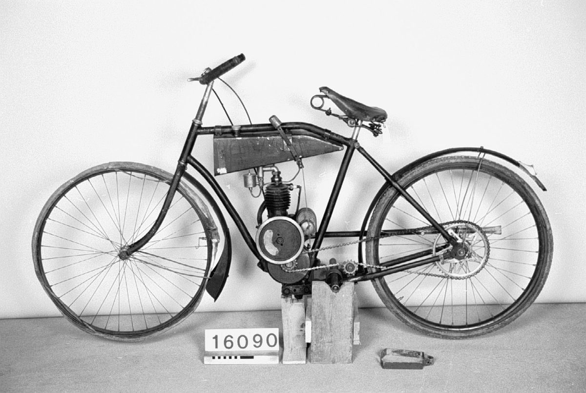 Cykelmotor med snarkventil som levererades med de engelska Villiersreglagen till styret, kedjehjul och drivkedja. EBE förgasare, SEM, Åmål magnet. Den första ramen (TM 16.091) som ägaren använt var en cykelram från 1910-talet. Den nuvarande kan tidigare ha använts i en 98 cc lättviktare. Hemgjorda tankar för bensin och olja samt reglage på dessa. Motornummer 1107.  Encylindrig luftkyld fyrtaktsmotor, cylindervolym 184 cc, cylinderdiameter 60 mm Slaglängd 65 mm. 2 hk vid 2000 varv/minut Förgasare: Ebe, magnet: SEM Bränsleåtgång ca 1 l. på 4 mil = ca 0.25 liter per mil. Frikoppling men inga växlar Högsta fart 60 km/timmen