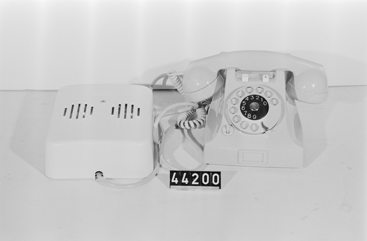 Telefonapparat BC 667 för AT-system, anknytningsapparat (chefsapparat) till sekreterarapparat BC 666. Bordapparat modell m50 av grå plast med apparatklocka som strömmatas från batteri alt. batterieliminator, två tryckknappar, apparatsnöre anslutet till väggplint A0029497 med växelströmsklocka och omkastare för in- och urkoppling av växelströmsklockan.