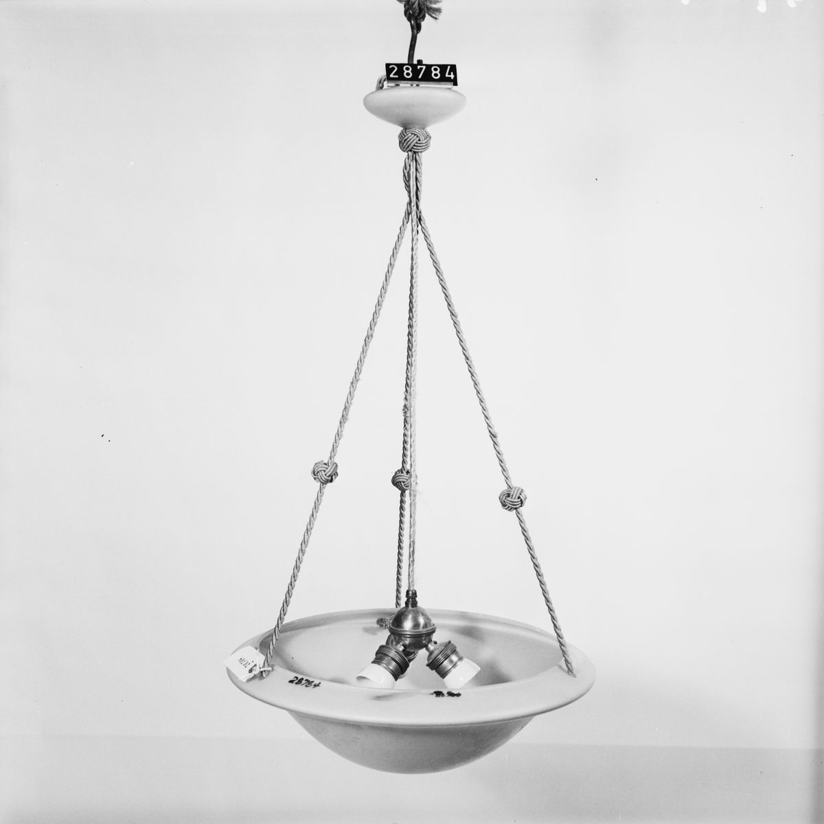 Armatur för rumsbelysning med skål av glas med snören, jämte tre hållare för glödlampor och ledning.