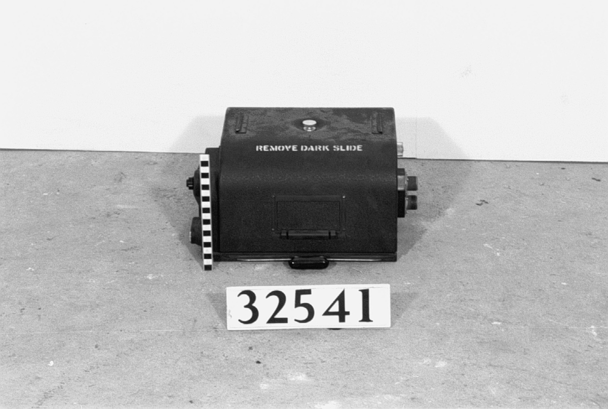Flygseriekamera, format 82 x 8 tum, för flygfotografering under mörker med fotobomber som ljuskälla. Kameran är elektriskt driven och består av kamerahus med objektivtub, objektivslutare och drivverk, elektrisk drivmotor, skyddslock för objektiv, 2 st. kassetter fotocellaggregat, 2 st. elledningar, förvaringslåda. 24 cm. operforerad film användes. Kassetten rymmer 60 m film motsvarande 250 exponeringar. Objektivet Kodak-Ektar, brännvidd 30 cm. Ljusstyrka 1#2.5. I koffert med hörnbeslag och läderhandtag. En kassett separat. Tomspolar - ingen film. Lådans längd: 580 mm, bredd: 500 mm, höjd: 740 mm.