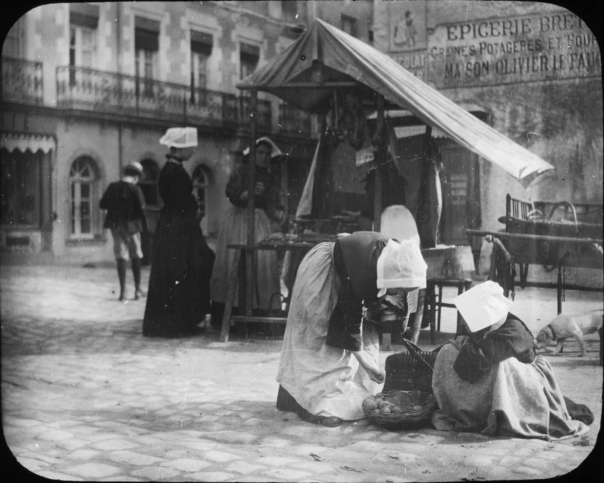 Skioptikonbild med motiv av kvinnor vid marknadsstånd i Vannes.
Bilden har förvarats i kartong märkt: Resan 1908. Vannes. XXI.