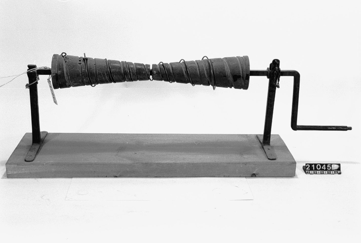 Maskin för spinning av möbelresårer. Maskinen består av en vev av fyrkantsjärn på vilken två koniska trärullar monterats för att spinna tråden till koniska resårfjädrar. Veven vilar sedan på två konsoler av järn.
Tillbehör: Lösa delar: 1 st. färdig resår, 1 st. ofullbordad i maskinen, båda från år 1942 av järntråd då donator vid tillfället saknade ståltråd.