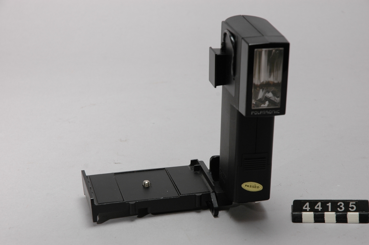 Direktbildskamera Polaroid Land Camera SX-70 med väska, blixthållare, stativhållare, trådutlösare samt 25 st filter. Kromplastad SLR kamera (Single-Lens Reflex) med påklistrad läderdekoration, 4-elements 116 mm f/8-f/22 glaslins och elektroniskt styrd slutare med hastigheter från 1/175 upp till 10 sekunder. På kamerans front finns avtryckarknappen, exponeringsmätarens sensorfönster, reglage för skärpeinställning och kompensering av den automatiska exponeringsinställningen och en sockel för att ansluta en modul med 10 st blixtlampor. Manuellt fokus kan ställas in ner till 26,4 cm. SX-70 var den första SLR-kameran på marknaden för direktframkallade bilder och den första som använde Polaroid's  nya integrerade färgfilm som framkallades i fullt dagsljus utan manuella ingrepp av fotografen. Filmpacken, som bestod av 10 bilder med formatet 7,9 x 7,9 cm, innehöll dessutom ett tunt platt 6-volts batteri av zink-klorid som försörjde exponeringselektroniken, motorn till filmframmatningen och blixtlamporna. Filmens hastighet var ASA 150. Kameran kan fällas ihop till ett format som får plats i en kavajficka.
Tillbehör: Väska, blixthållare, stativhållare, två st. filter och trådutlösare.