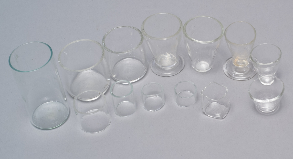 Nio små bägare av glas samt fyra ringar av glas.