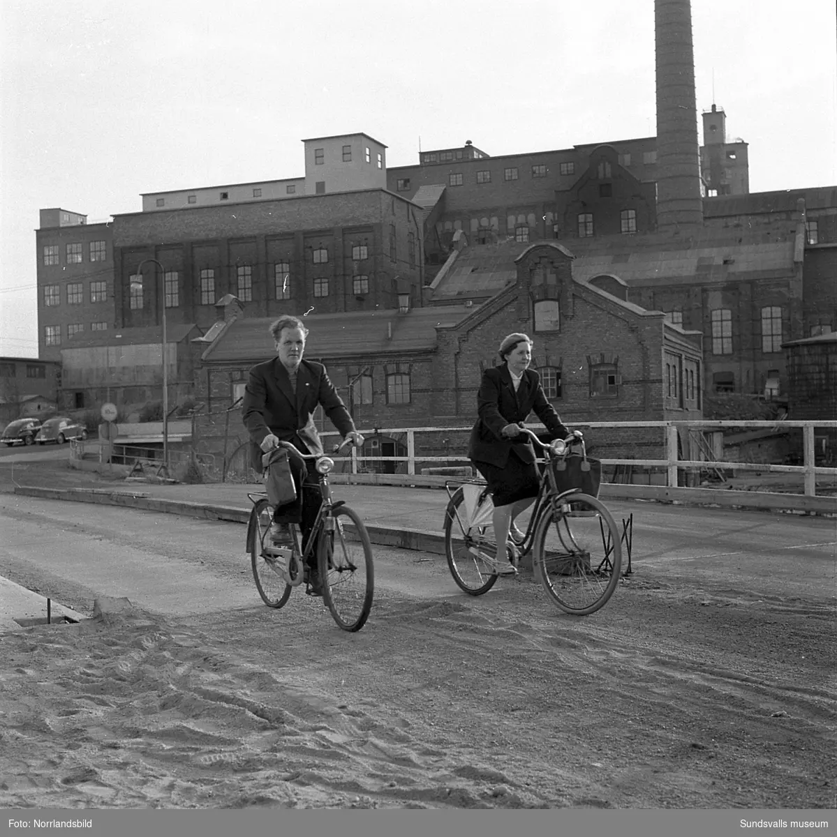 En man och en kvinna på sina cyklar vid Essviks sulfitfabrik.