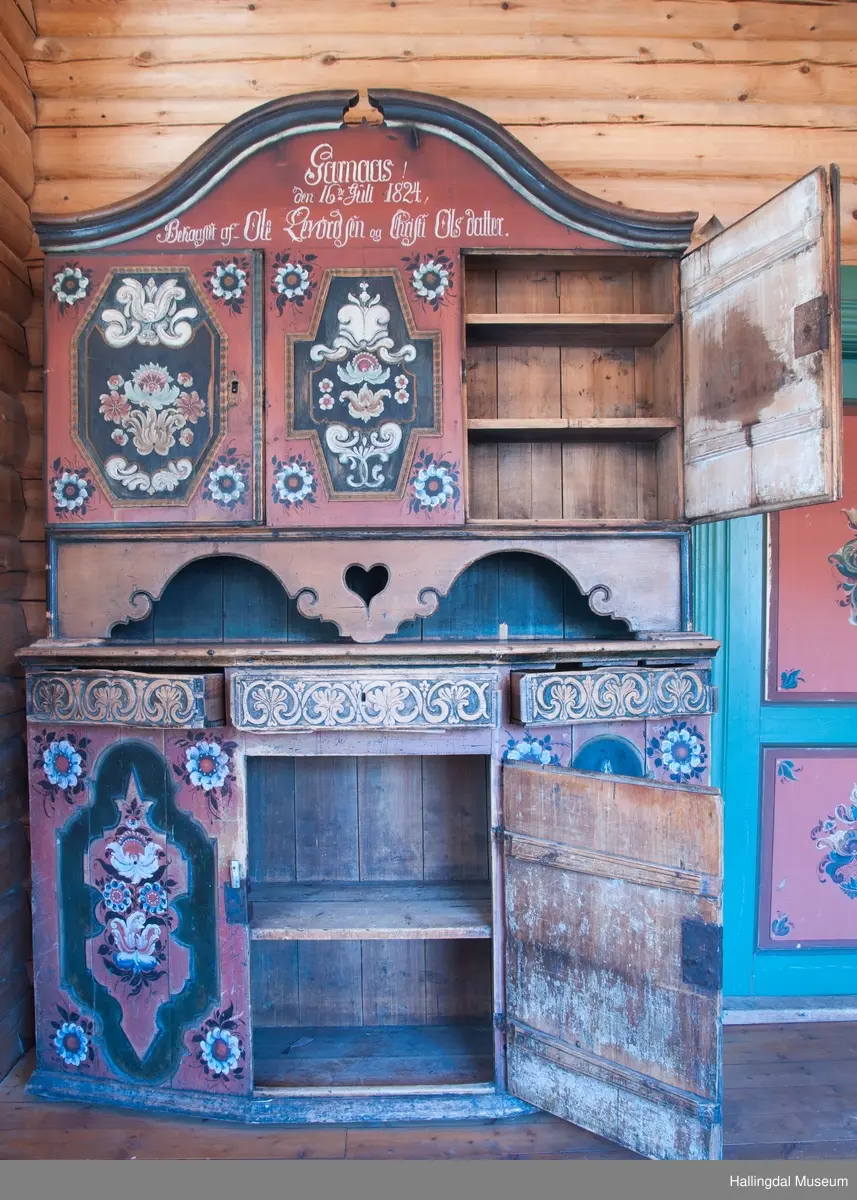 Delene festet med trenagler.  Høy, buet gavl med fremspringende kronlist som øverst har gjennomskåret omvendt hjerte.  Kronlist har hulkil og vulst, og fortsetter på sidene av overskap.  Overskapets front delt i tre felt, med en dør i hvert sidefelt.  Dørene er hengslet til skapets sider.  Hengslene av jern og festet på overkant og underkant av skap og på overkant og underkant av ramme.  Dørene har to profilerte labanker i spor på innsiden.  Låskasetter innfelt i dørblad.  Låsskiltene mangler.  Nøkkel med kløverformede hoder, profilert. En skillevegg midt i overskapet.  To hyller i hvert skap.  Dørene og midtfelt har speil med fyllinger og utskjæringer, akantus i relieff på speilflatene.  Dørspeilene er ovale, åttekantede.  Speil i midtfelt har tilnærmet korsform.  Skjenken har utskåret forplate, i tunger.  Under midfelt får forplaten helt ned til skjenkeplate med gjennombrutt hjerte.  Halvrunde åpninger i hver side. ..........