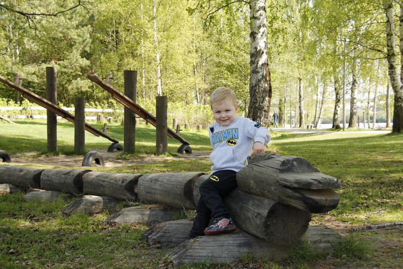 Liten gutt sitter på tømmer i lekeparken på Fetsund lenser (Foto/Photo)