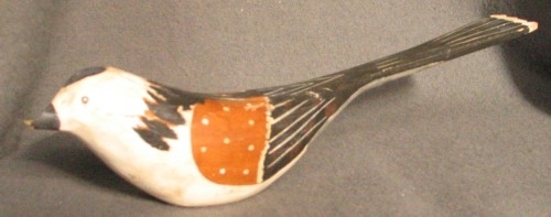 Dekormålad fågel i trä. Vit och svart fågel med bruna vingar.Fågeln gjord av "Pinkatorparn" Sven Dal. 
Fåglarna målades av olika kvinnor på bygden.