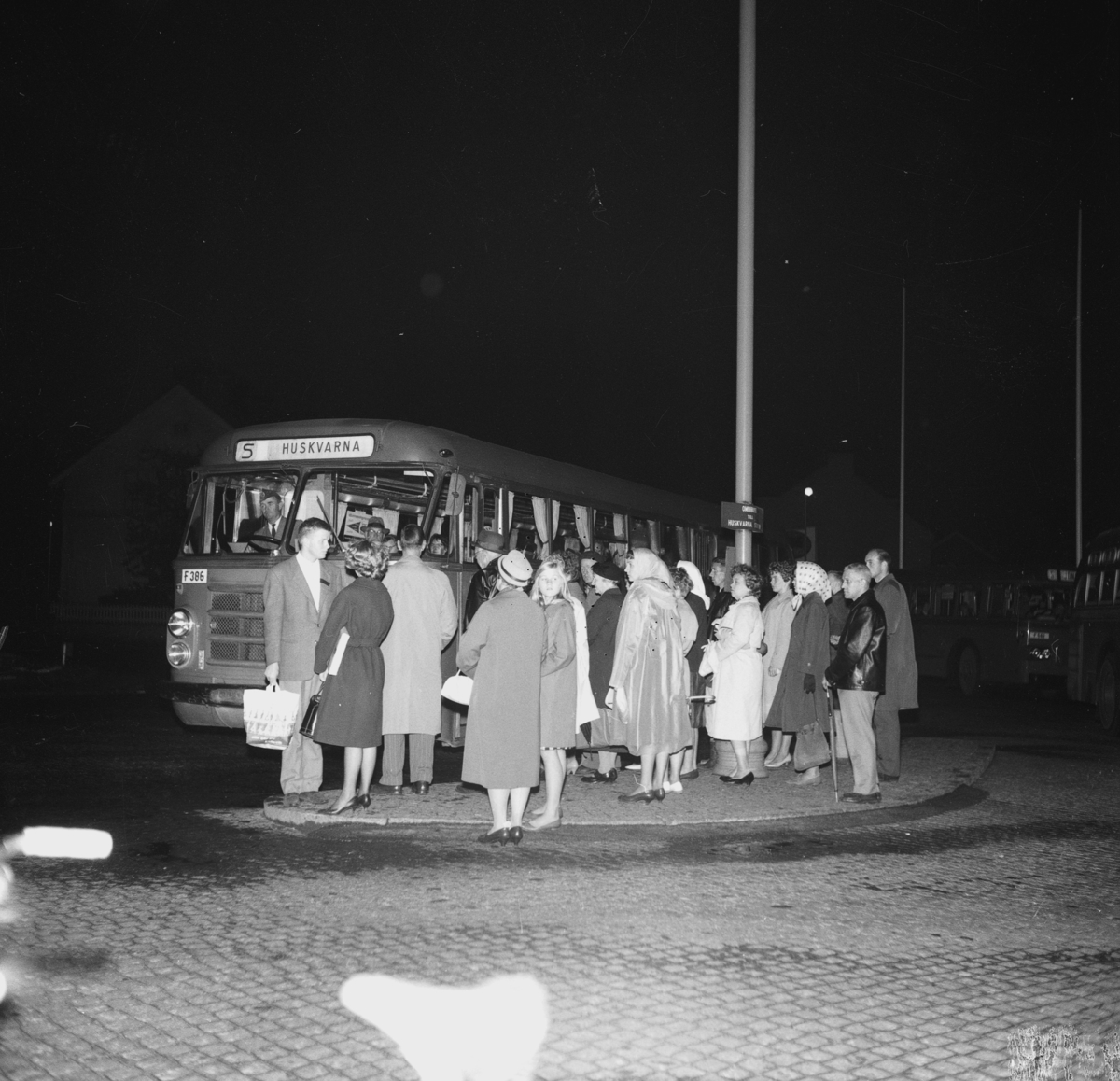 En grupp människor står vid en buss på esplanaden i Huskvarna.