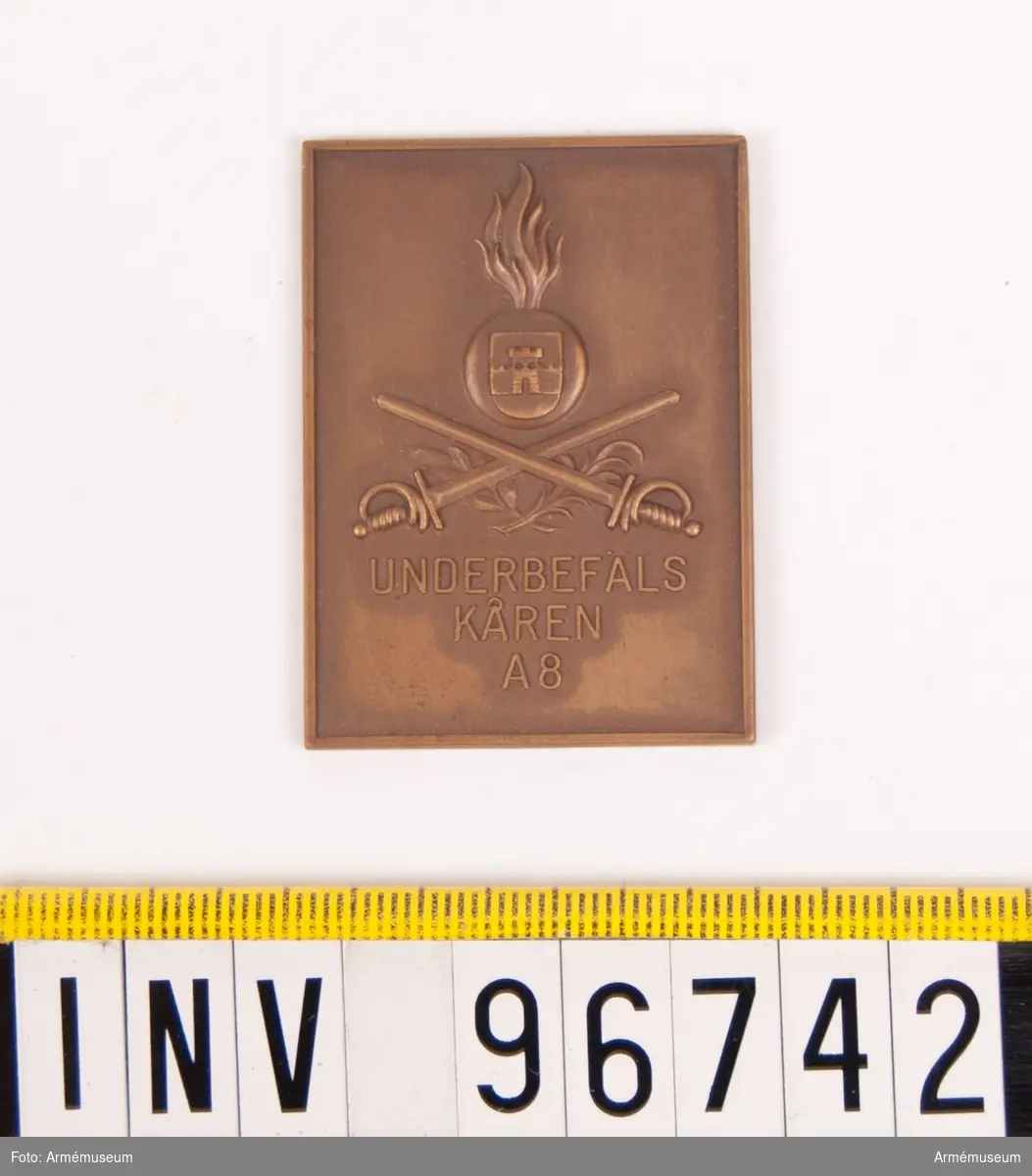 Plakett i brons för Underbefälskåren A 8.
Plakett med granat och Bodens vapen därunder korslagda värjor och stiliserade kvistar samt inskription UNDERBEFÄLSKÅREN A 8.
Stans nr 14397.
Stans härdad 1942-09-18.