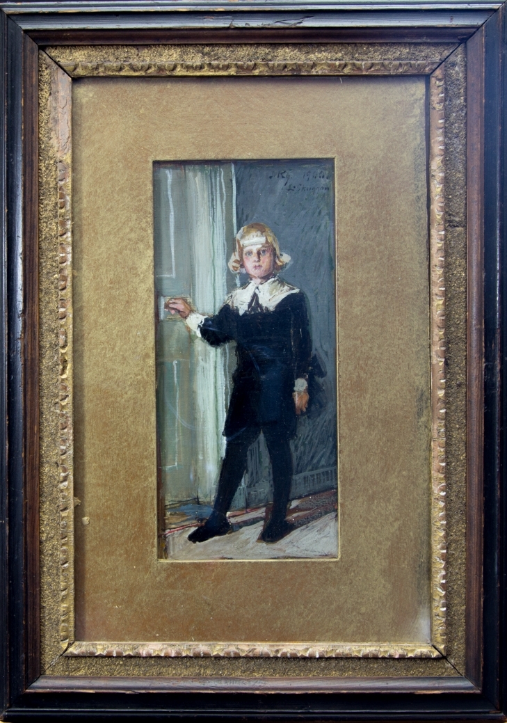Porträtt föreställande en ung pojke, Rolf Kronberg, stående i helfigur i ett bostadsrum. Klädd i svart pageliknande dräkt med vit krage och vita manschetter. Han håller ena handen på handtaget till en dörr.