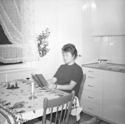 Turid Karikoski sitter og leser ved kjøkkenbordet hjemme i H