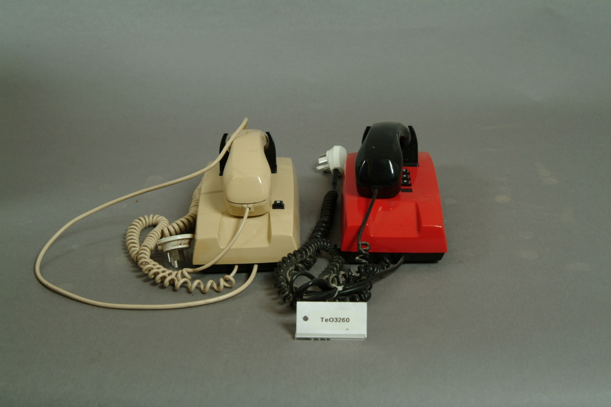 Telefonapparat Diavox, 2 st, för AT-system, huvudapparat, anknytningsapparat till abonnentväxel och sidoapparat. Vänster apparat: Väggapparat med kåpa och mikrotelefon i beige plast, knappsats med med tolv knappar för tonval, R-knapp för aktivering av tilläggstjänster under pågående samtal och apparatsnöre med proppanslutning. Höger apparat: Väggapparat i plast med röd kåpa, svart mikrotelefon, knappsats med tio knappar för impulsval och apparatsnöre med proppanslutning. Båda apparaterna har högohmig ringklocka reglerbar i tre steg, elektretmikrofon och elektronisk talkrets med automatisk dämpningskompensering.