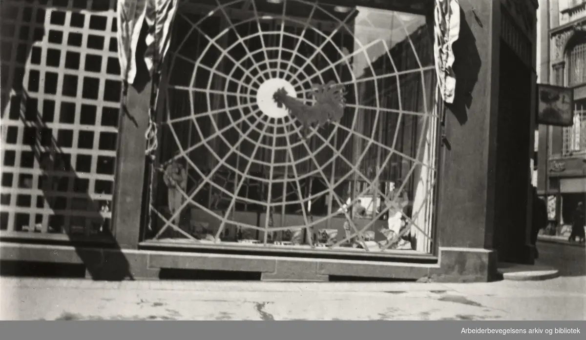 Ole M. Engelsens fotografier fra okkupasjonsårene i Oslo. Slik ble vindusrutene sikret for å hindre at glasset skulle splintres ved flyangrep..Sætre kjeksfabriks utsalg i Karl Johan gate 18, mai 1940.