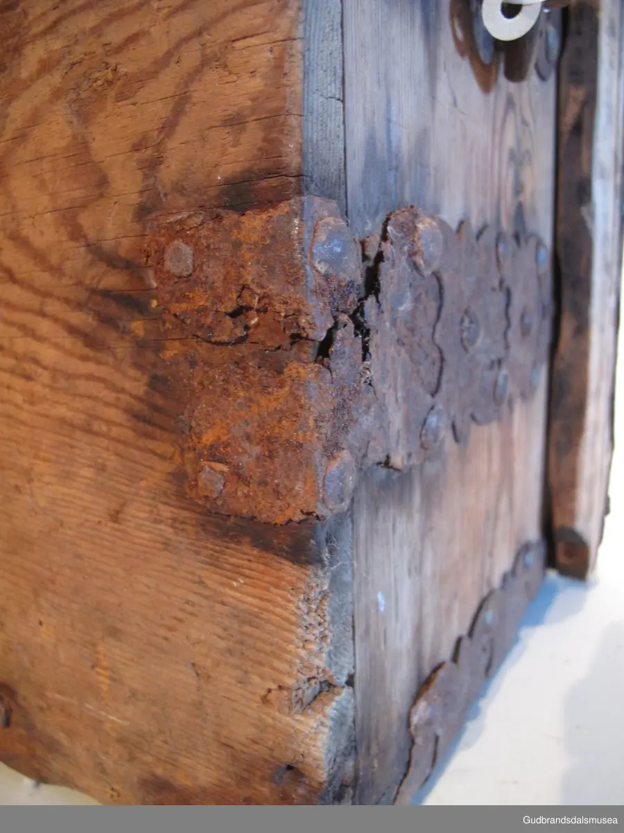 "Ferdaskrin. Umalt. Over heile skrinet går det beslag med innhogga stjerner og hjerter. Fra Østre Gausdal. Merknad 2, også kalla Føringsskrin" (Jf. Katalog for Lom Bygdesamling, 1925).
Skrinet har 1 rom. LOKK: satt sammen av 3 bord, holdt sammen av sidelister på innsiden og jernbeslag langs sidekanter på oversiden. Hengslet med 2 hengselbeslag på innsiden og  2 på utsiden av bakstykke.  1 stk. låsbeslag på innsiden av lokk.
SKRINSIDER: gjæra sammen, holdt sammen av hjørnekantbeslag utvendig; profilerte toppkanter.
BUNN: satt sammen av 2 bord, festet til skrinrammen med trenagler. Er i tillegg opprinnelig holdt på plass av 10 beslag festet til skrinbunn og sidestykker. Jernhandtak på hver side.
BESLAG: 5 jernbeslag i lengderetning på lokk. Tilsvarende 3 beslag og 2 hjørnebeslag på front og sider. Alle beslag er festet med jernnagler.
DEKOR. Ingen skurd- eller malingdekor. Skrinet har i stedet jernbeslag med utskårne hjerte- og stjerneformer som dekor. Muligvis fra 1600-tallet der treskurden ikke var fremherskende. Liknende dekor ses på LBY0319.
BRUK. Før kofferten kom i bruk hadde man reiseskrinet, som ble brukt til oppbevaring av bl.a. klær, verdisaker og mat på reiser. Skrinet hadde ofte et eller to mindre, smale rom langs den ene skrinsiden og ett større rom. De fleste reiseskrin var i tillegg forsterket med jernbeslag langs alle kanter og med en solid nøkkelhullås til sikring mot støt, slag og tyveri.