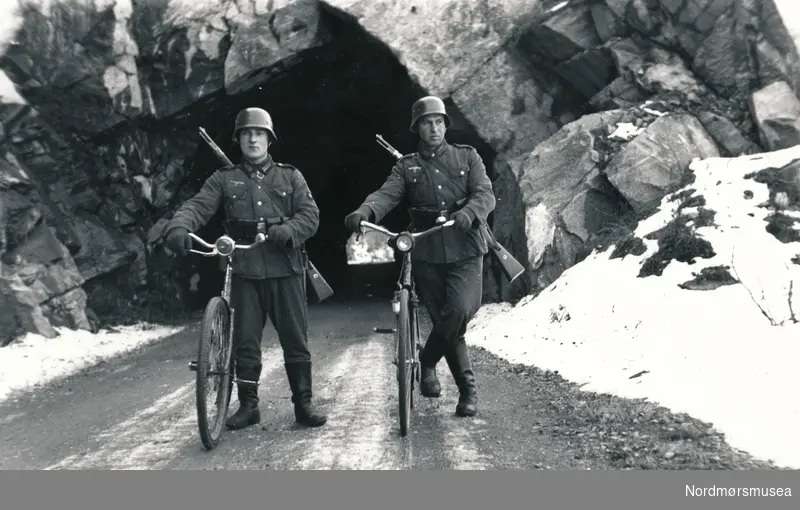 To soldater som står utenfor en tunnelåpning. Muligens tunnel ved Holbuvatnet