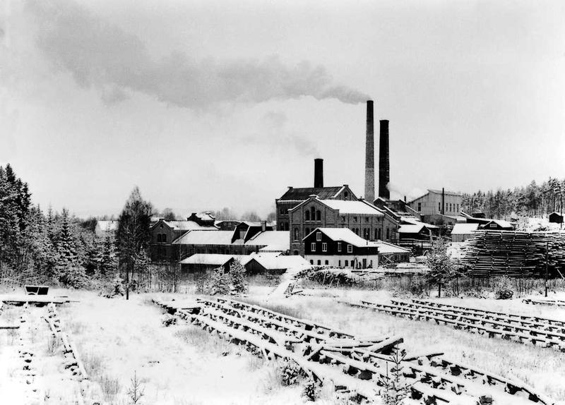 Klevfos cellulose & papirfabrik sett fra sør. Ryker fra pipa og landskapet er dekket med snø.