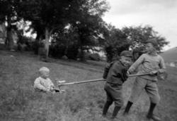 Fotografi av to unge gutter som bruker en rive til å dra en 