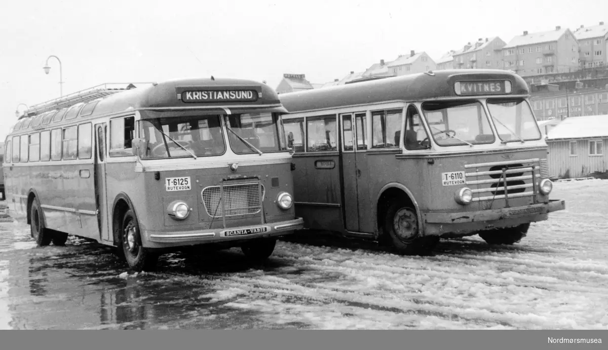 Bussene er fra venstre T-6125 og T-6110. T-6125 er 1961-modell (reg. mai 1961) og T-6110 var 1955-modell som selskapet solgte i 1965. Fotoet må da stamme fra tidsrommet 1961-1965. (Info: Sveinung Berild - 16.10.2016) -  KFB Frei Billag. Foto trolig fra Rutebilsentralen, bussenes ekspedisjon i Vågen på Kirkelandet i Kristiansund, hvor vi ser fra to rutebusser side ved side.  Fra Nordmøre museums fotosamlinger.