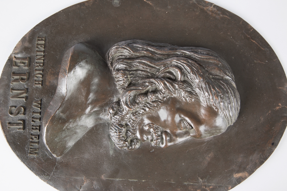 Relieff av Ernst's hode og ene skulder på oval plate.