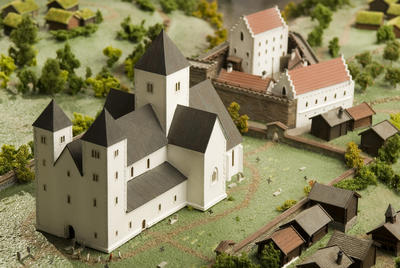 Modell av middelalderkatedralen, en basilika i hvit kalkstein med to vesttårn og hovedtårn. Modell av bispegården skimtes i bakgrunnen.