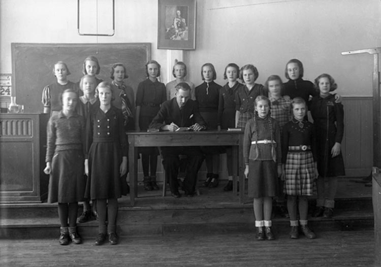 Foto av en skolklass med lärare, som samlats i ett klassrum.