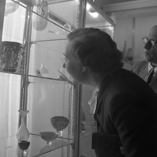 Glasdesigner Edvard Hald m.fl. som tittar på en glasutställning.