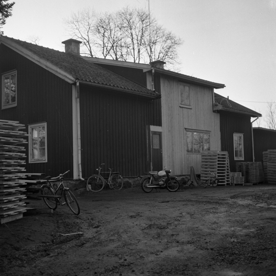 Foto av ett bostadshus (baksidan) med parkerade cyklar och en moped.
