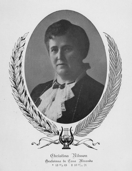 Porträttfoto av Christina Nilsson i oval ram med lagerbladskrans. Hon bär blus med s.k. jabot och halsband.