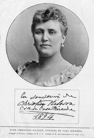Signerat foto (autotypi) av Christina Nilsson där hon bär klänning och örhänge. Under fotot dedikation på franska: "Un souvenir de Christine Nilsson, Ctesse de Casa Miranda, 1894".
