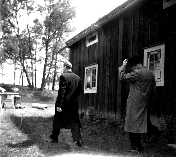 Foto på ett gammalt bostadshus och män som går.